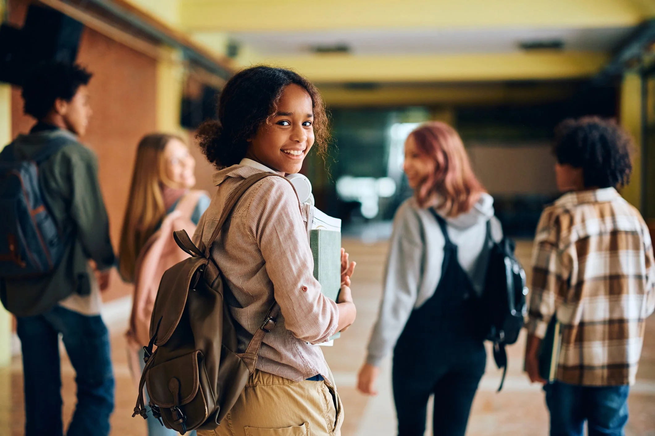 High school sophomore walking on campus with books and a backpack, beginning the college coaching journey